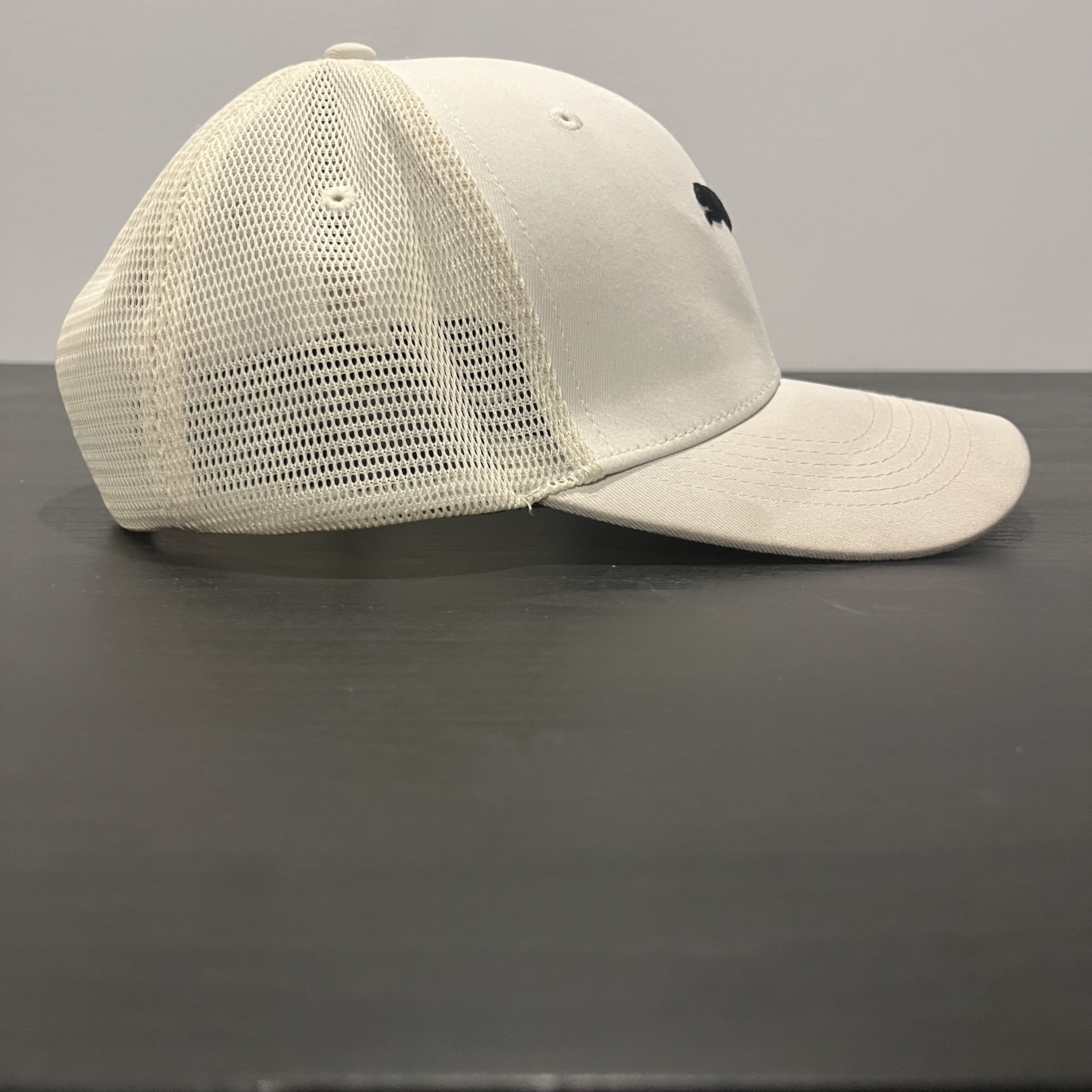 A white hat staged on a black table facing front