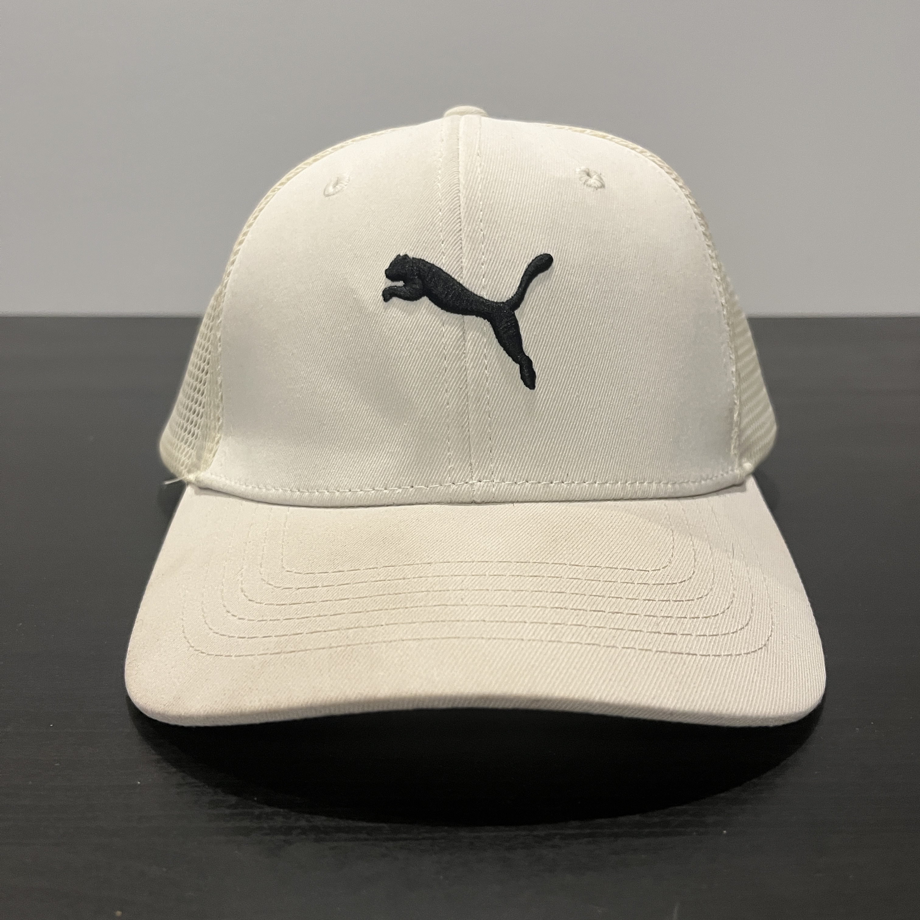 A white hat staged on a black table facing right