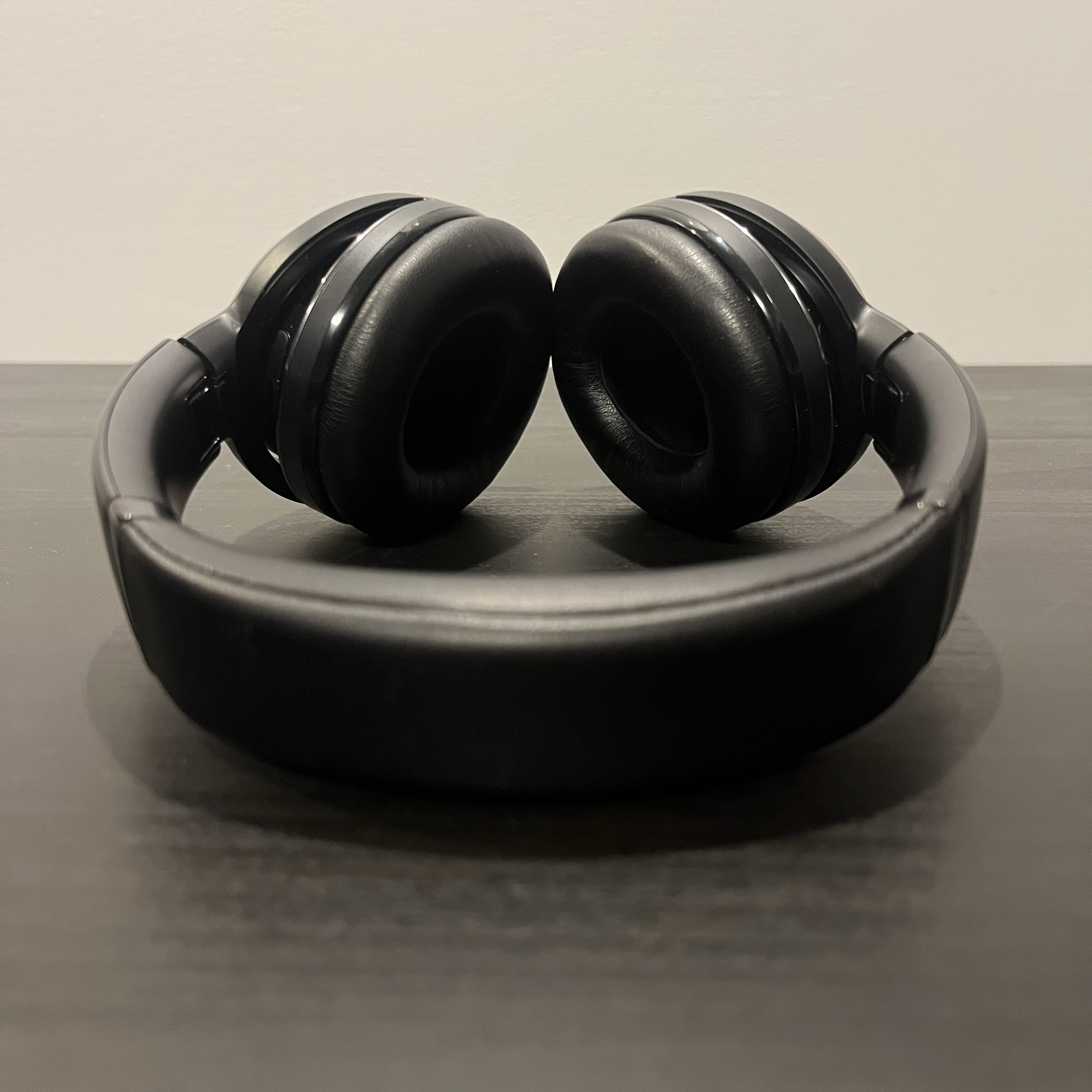 Black and silver over-ear headphones, staged on a balck table.