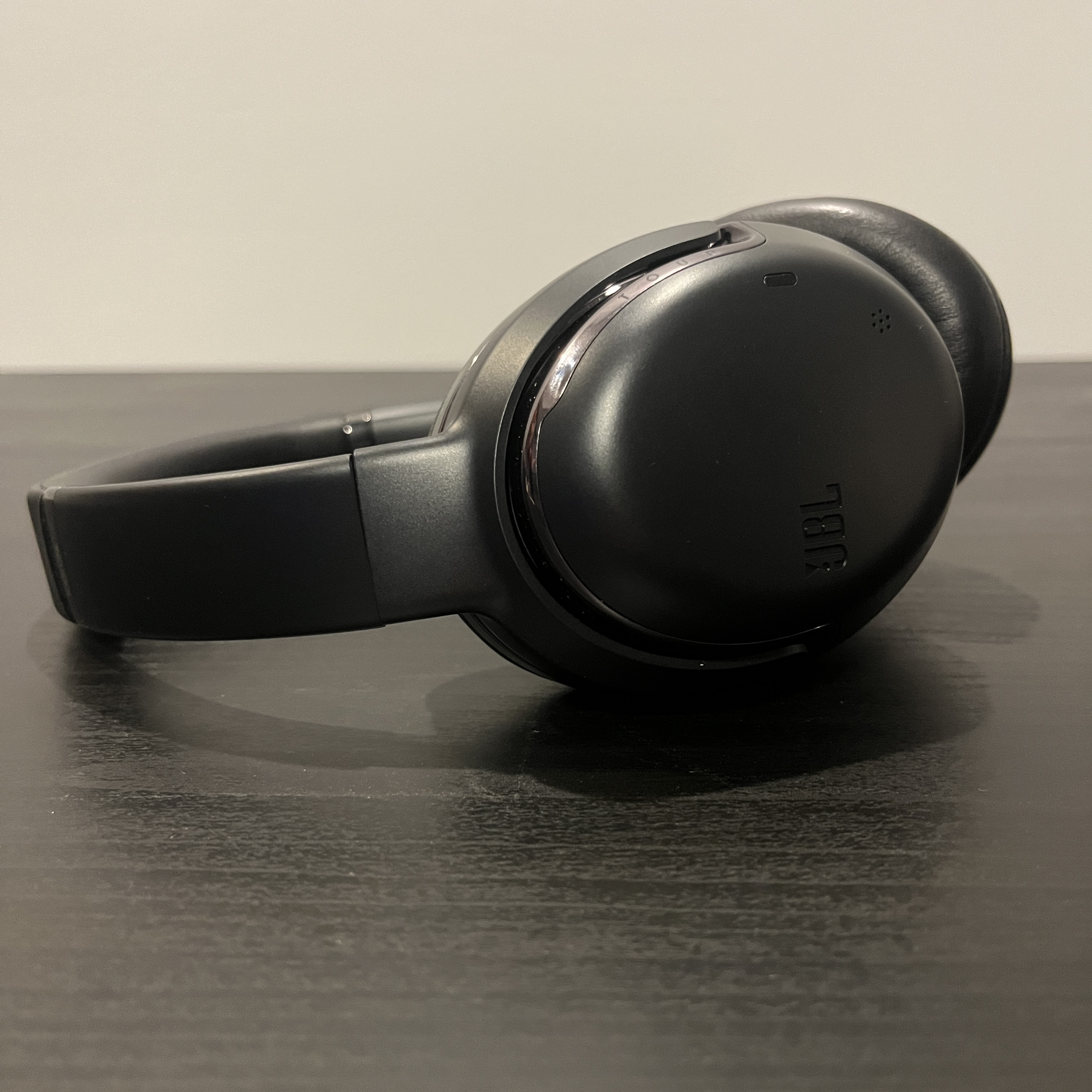 Black and silver over-ear headphones, staged on a balck table.